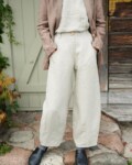 A woman in high waist barrel leg natural linen pants