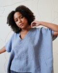 Model wearing a loose-fitting linen top with a V neckline