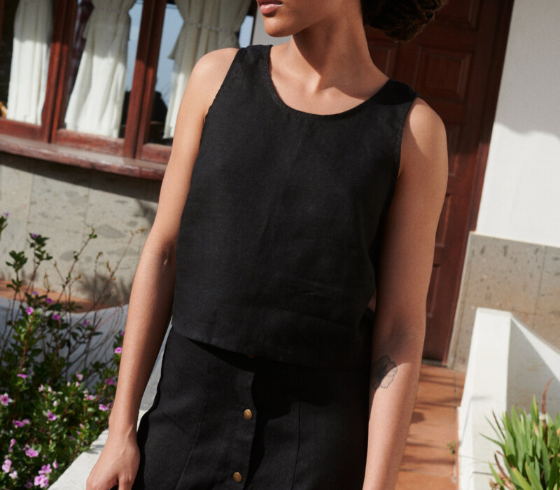 Model wearing a relaxed fit sleeveless black linen top and a matching linen skirt outfit
