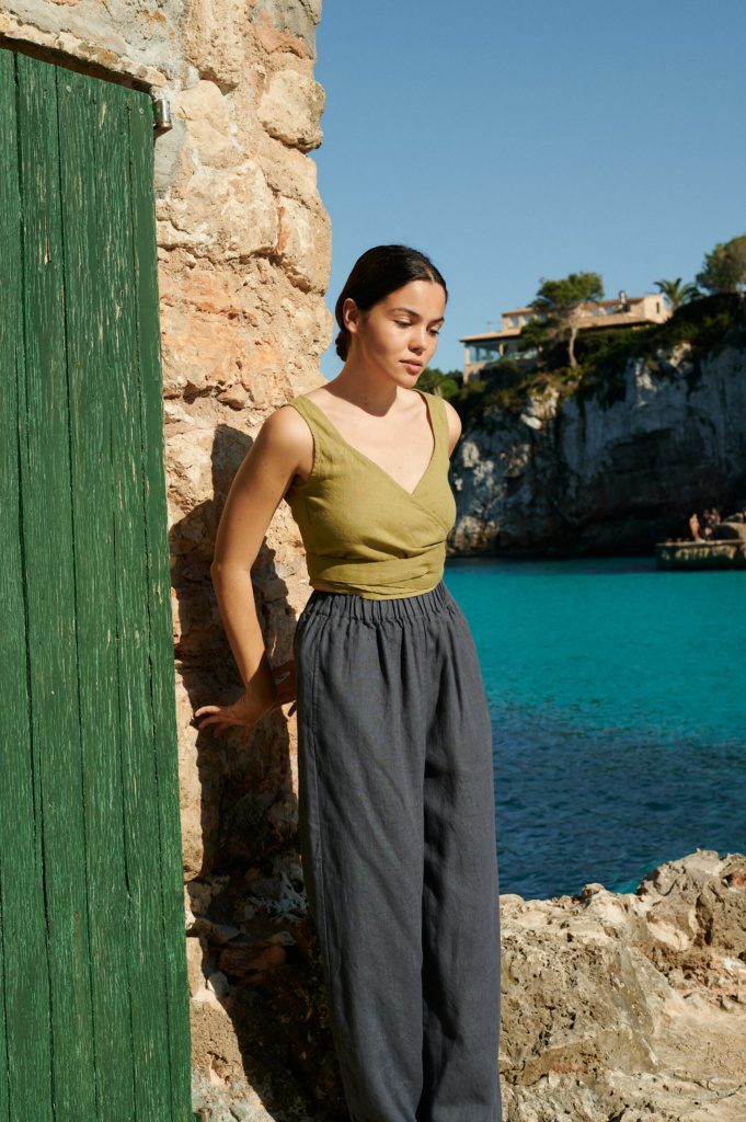 Model walking along the beach in wide-leg linen trousers paired with a sleeveless top