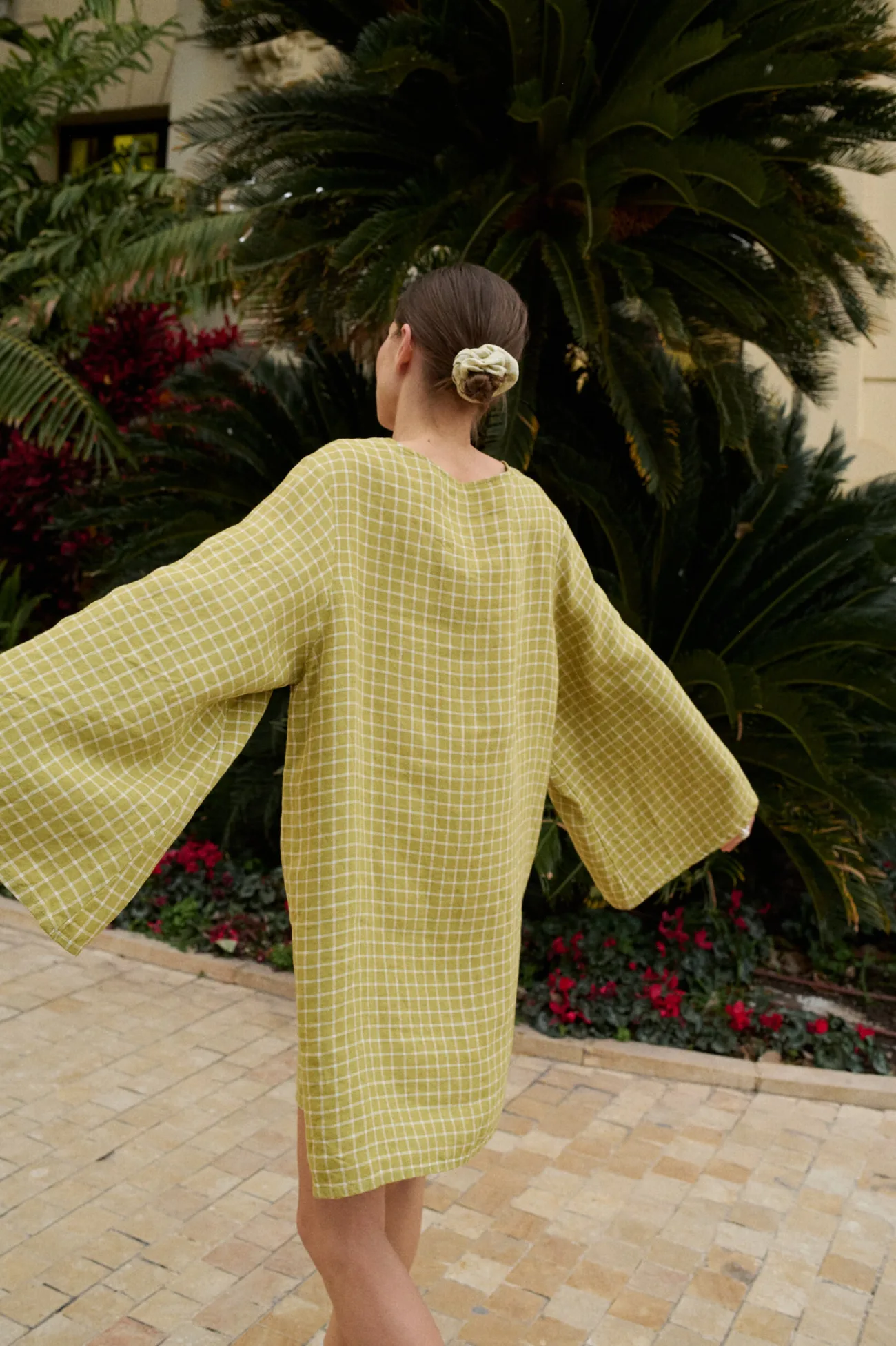 Model from the back wearing a relaxed pickle checks mini linen dress with long wide kimono-style sleeves