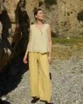 Model in a pale yellow checkered sleeveless linen top featuring a V-neckline, oversized fit, and a single side tie closure, paired with matching butter colored wide-leg pants for a breezy, effortless summer ensemble
