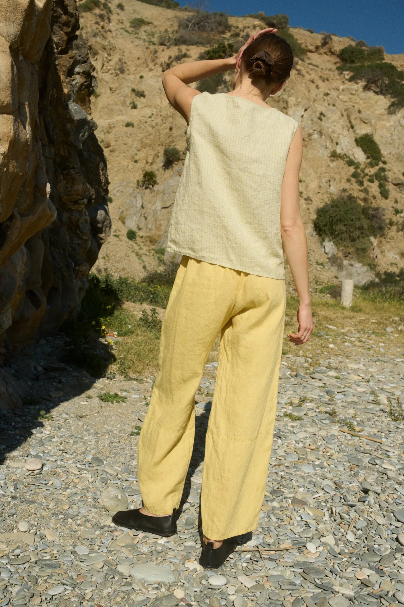Back view of a model wearing a pale yellow checkered sleeveless linen top paired with butter yellow wide-leg linen pants, showcasing the relaxed fit