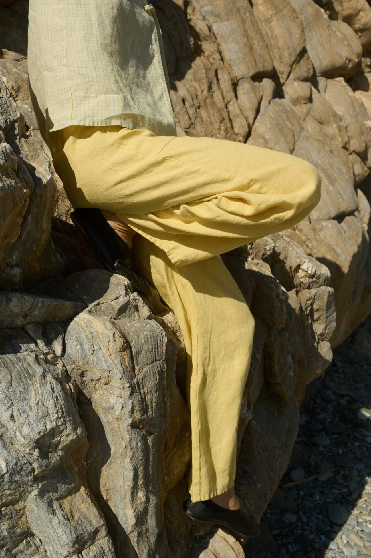 Side view of a model dressed in a ligh yellow checkered sleeveless linen top paired with butter yellow wide-leg linen pants