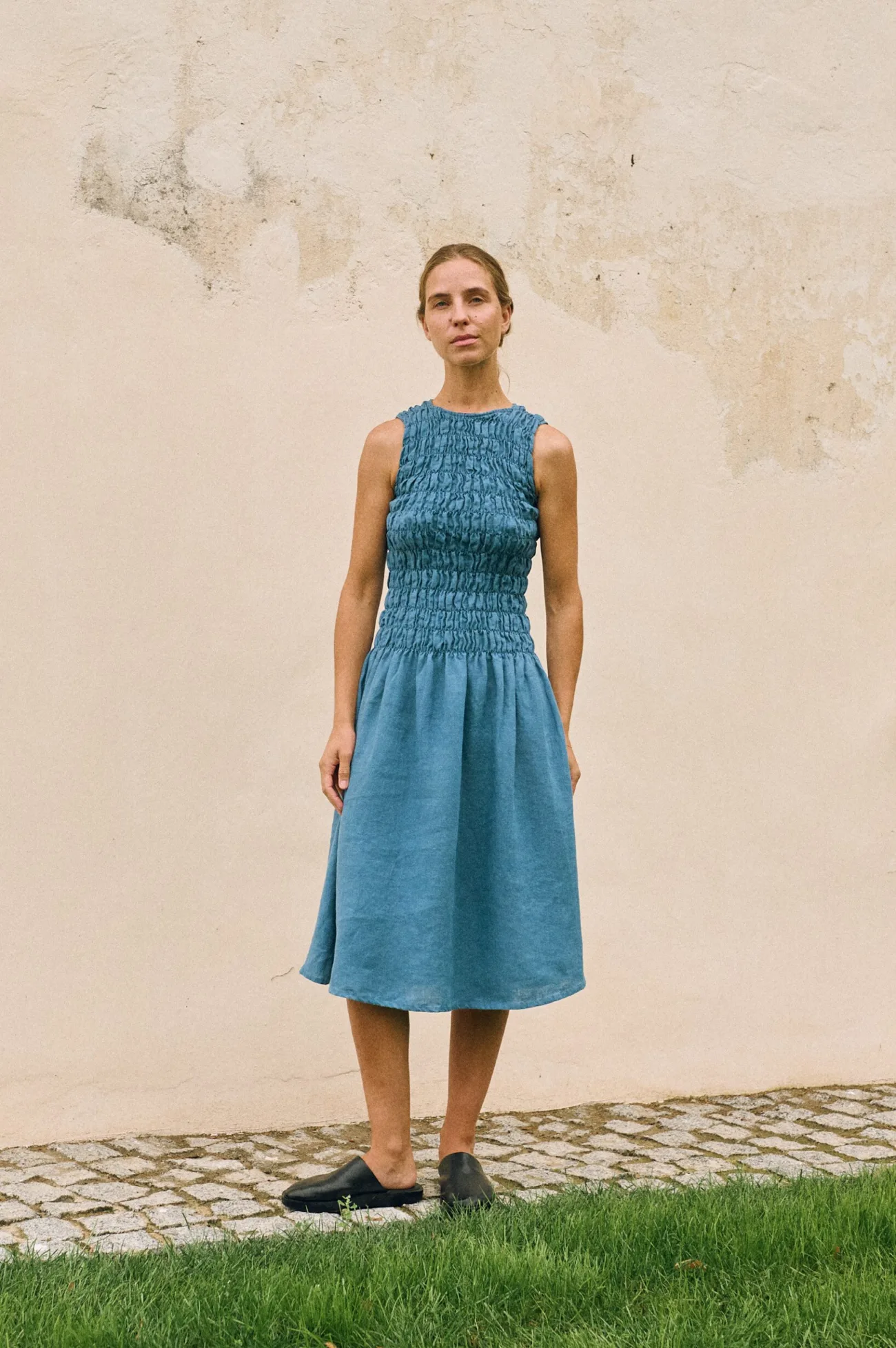 Stellar blue linen dress with a smocked bodice and sleeveless cut, shown full length on a model