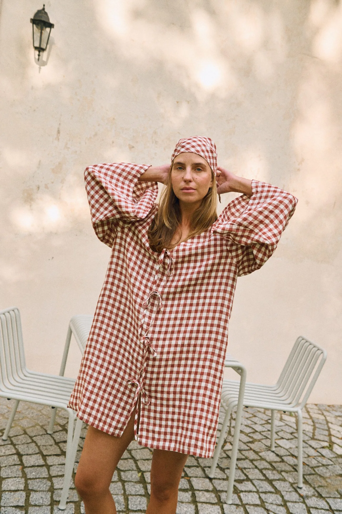 Front view of terracotta gingham mini dress with relaxed silhouette and statement sleeves