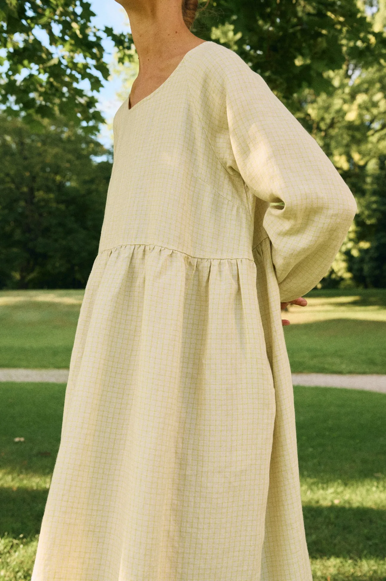 Side detail of apple checks linen dress highlighting gathered waist and airy fit