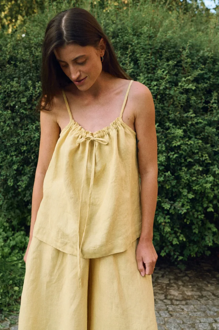 Detail view of yellow linen camisole top with adjustable drawstring front and thin straps