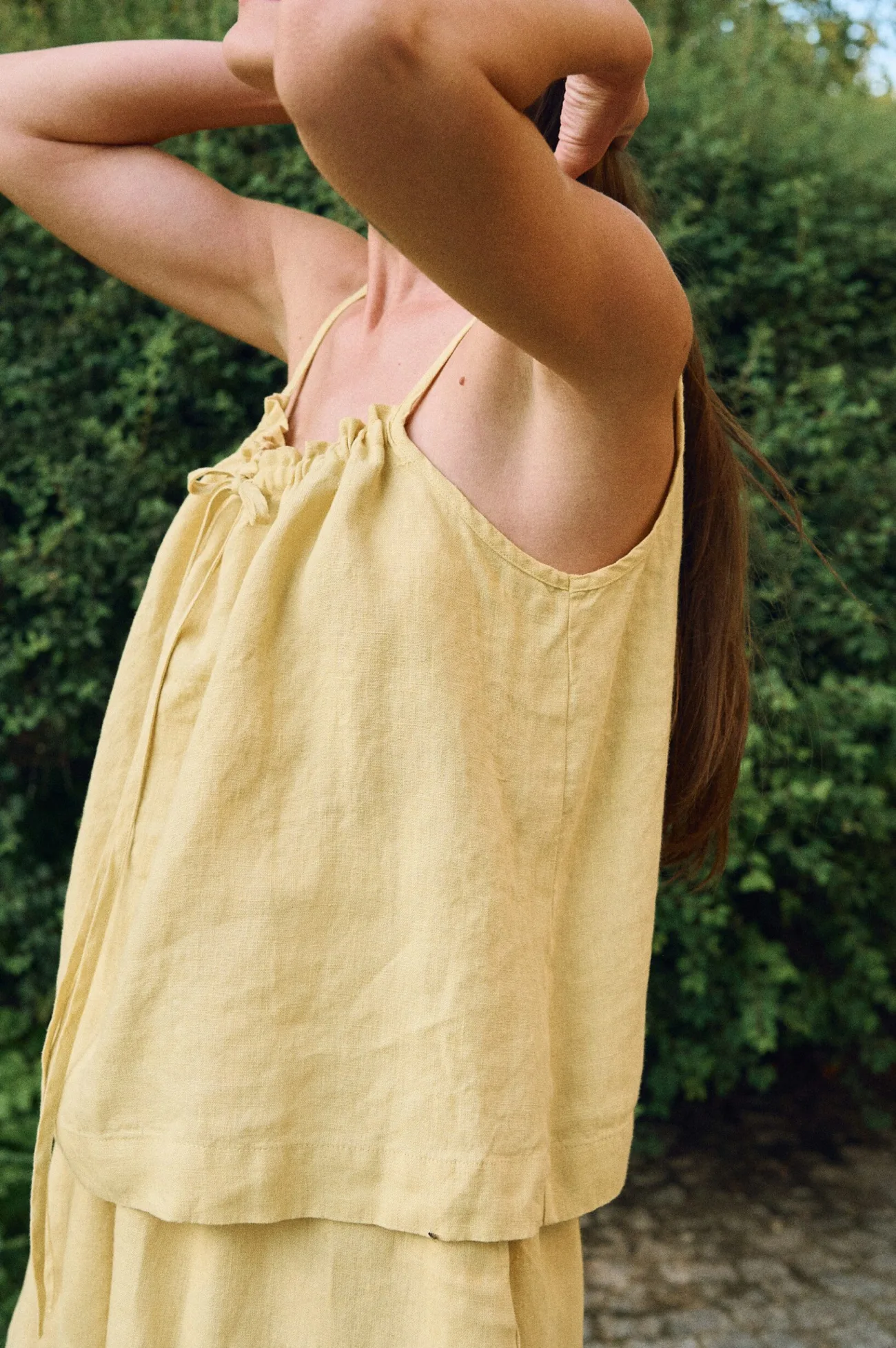 Yellow linen camisole top with adjustable drawstring neckline and thin straps, shown in side view