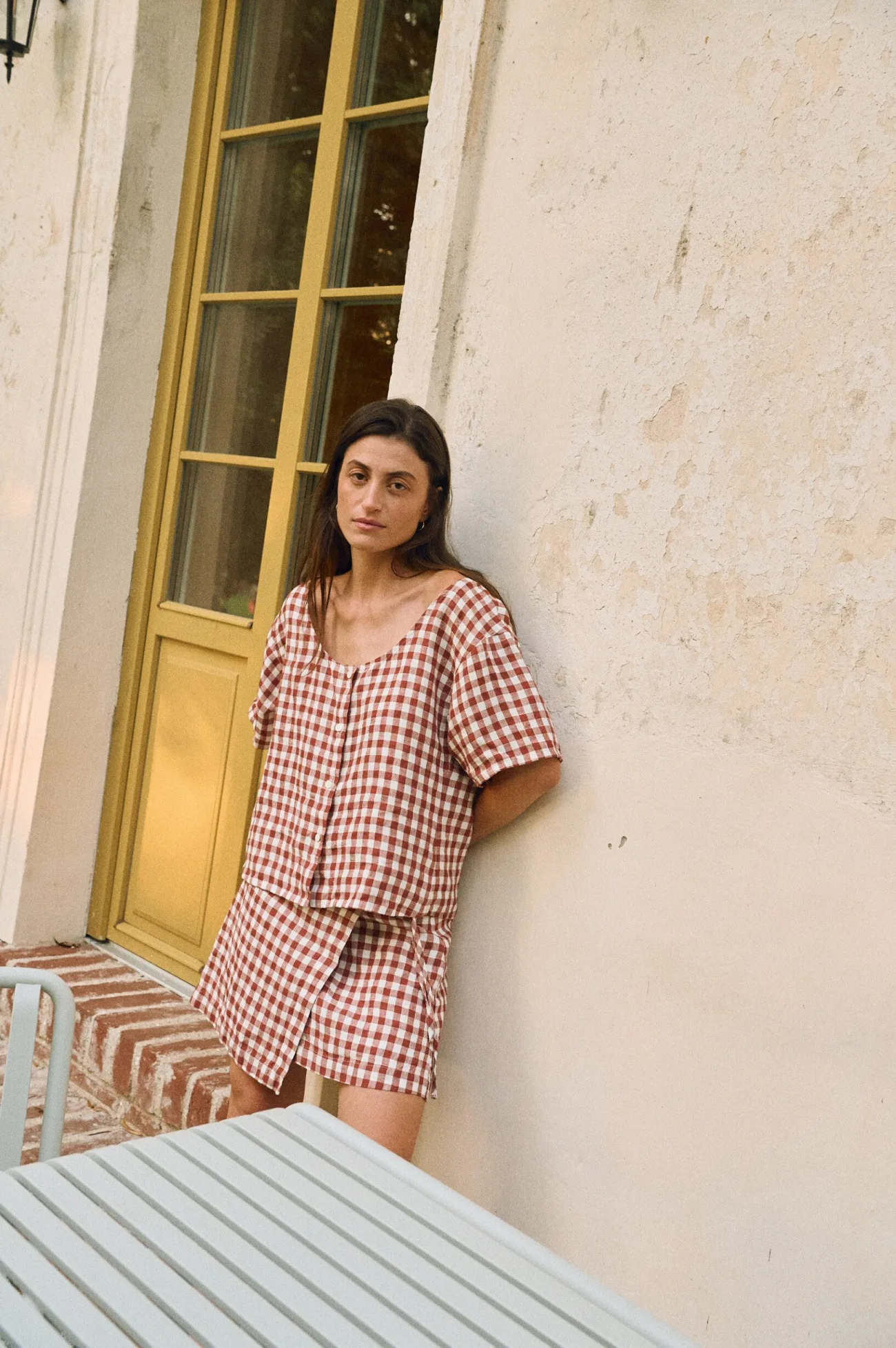 Woman wearing terracotta gingham linen short sleeve blouse with matching wrap mini skirt