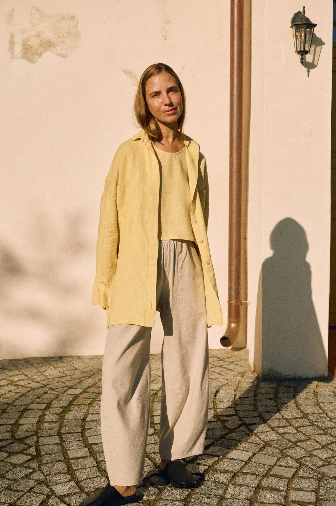 Butter yellow linen shirt worn open over butter tank and natural cotton-linen blend pants