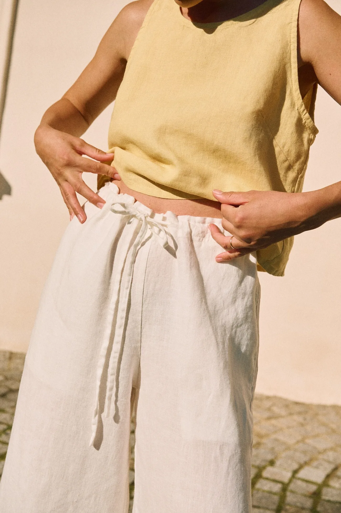 White linen trousers with adjustable drawstring waist paired with a butter yellow sleeveless linen top