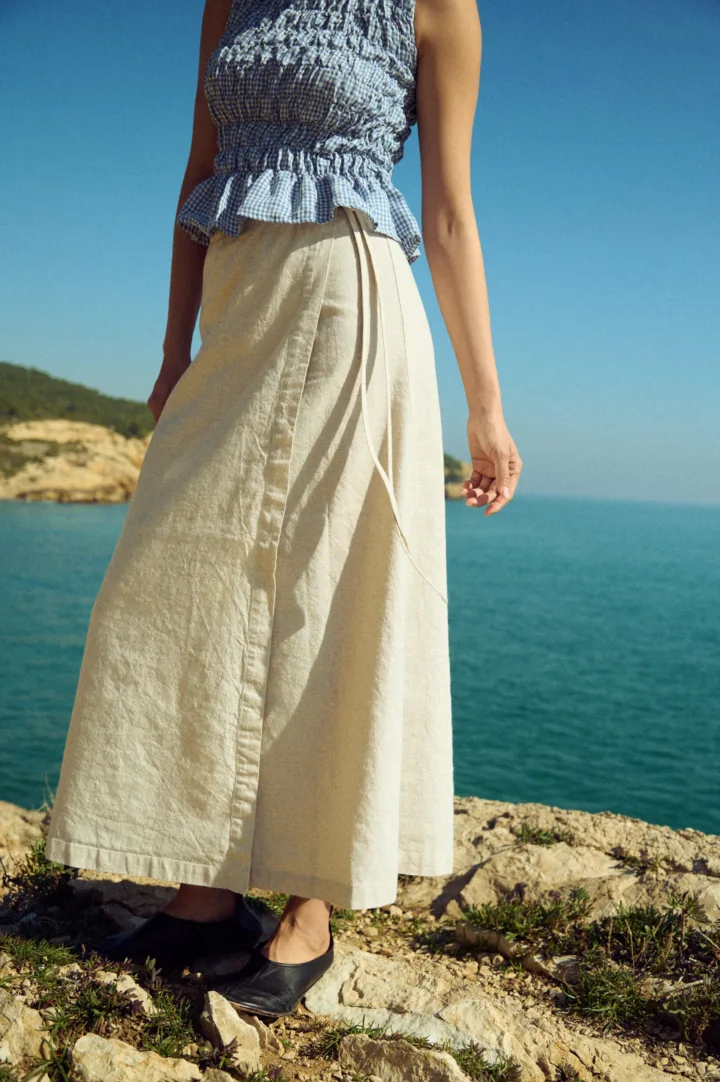 White cotton-blend wrap maxi skirt with tie closure, styled with a dusty blue mini gingham linen smocked peplum top