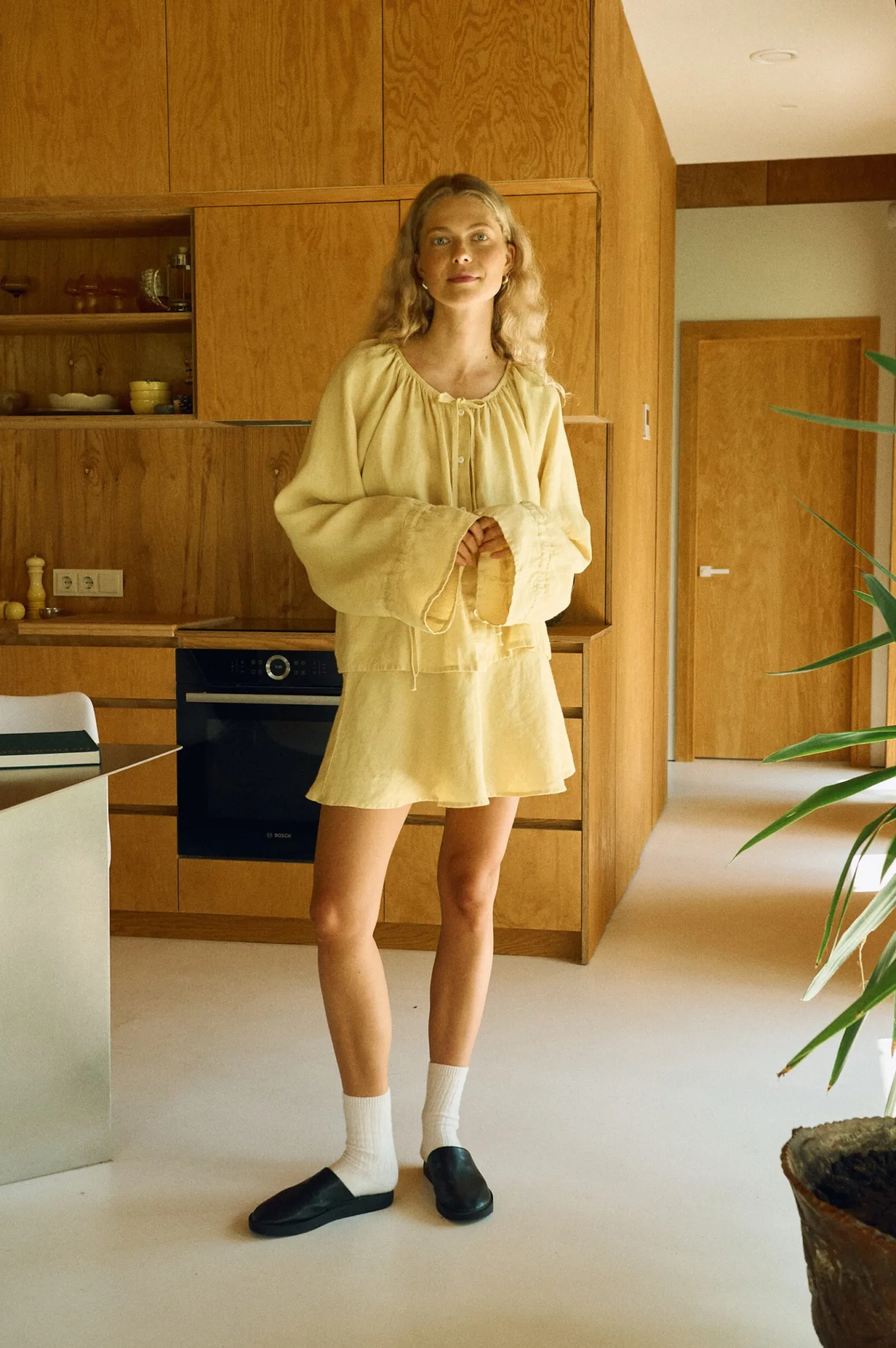Woman in butter yellow linen co-ord set with gathered neckline and drawstring ties