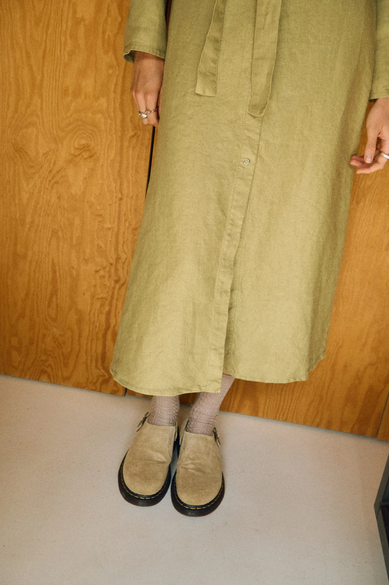 Lower view of an olive heavy linen midi shirt dress with a snap-front opening
