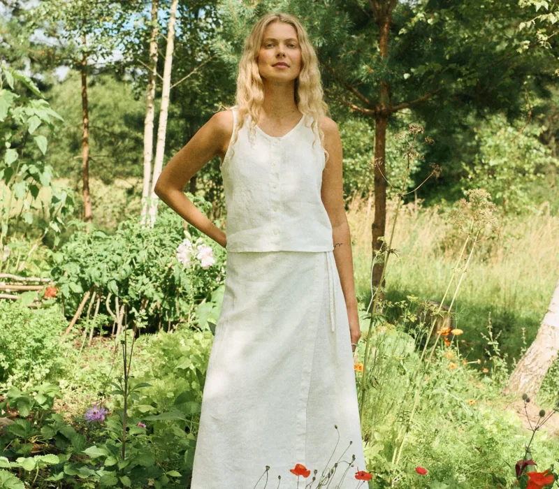 Sleeveless milky white linen set featuring a cropped button-up top paired with a high-waisted A-line wrap skirt