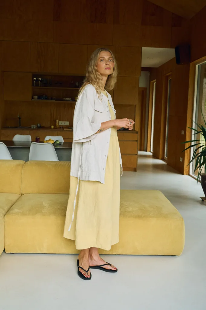 Layered linen outfit featuring a soft yellow sleeveless midi dress, styled with a natural linen cotton blend short-sleeve overshirt with decorative flap details and a relaxed fit
