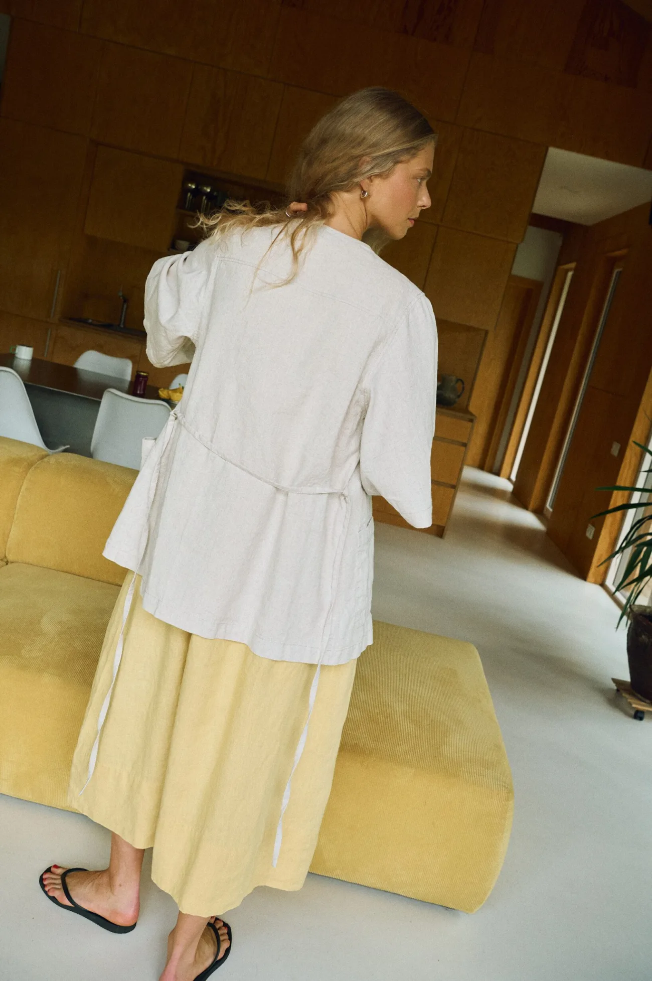 Back view of a breezy linen outfit featuring a pale yellow sleeveless midi dress styled with a loose natural linen-cotton overshirt