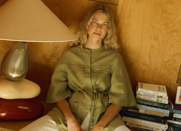 Seated model in olive linen overshirt paired with natural linen cotton trousers, relaxed full outfit