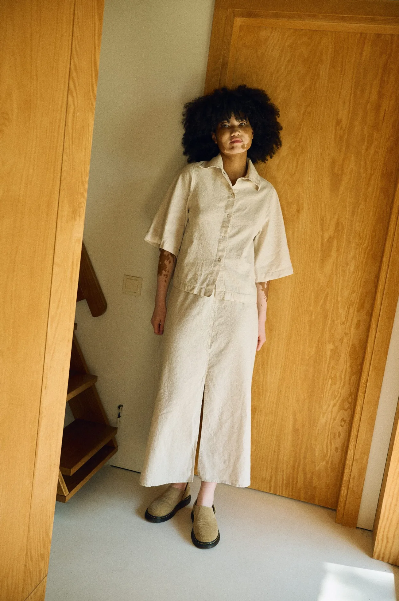 Full front view of a neutral-toned linen-cotton outfit featuring a short-sleeve collared button-up shirt paired with a high-waisted midi skirt with a front slit
