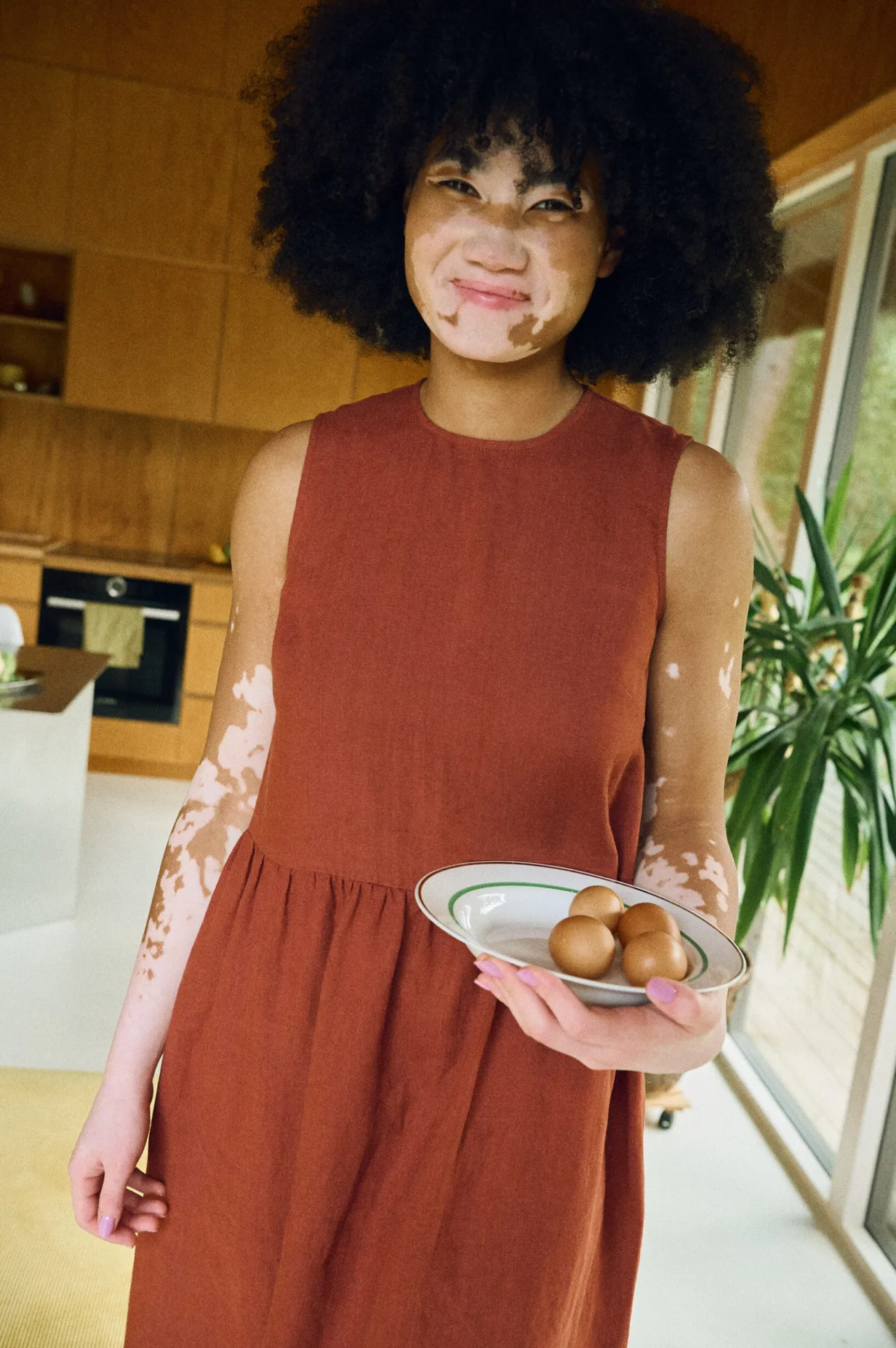 Front view of a sleeveless terracotta linen dress with a smooth, structured bodice and a gently gathered skirt