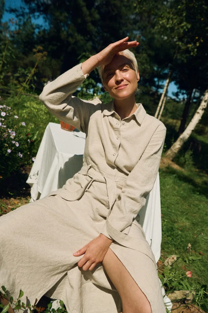 Natural utility dress shown while sitting, highlighting its comfortable, relaxed fit