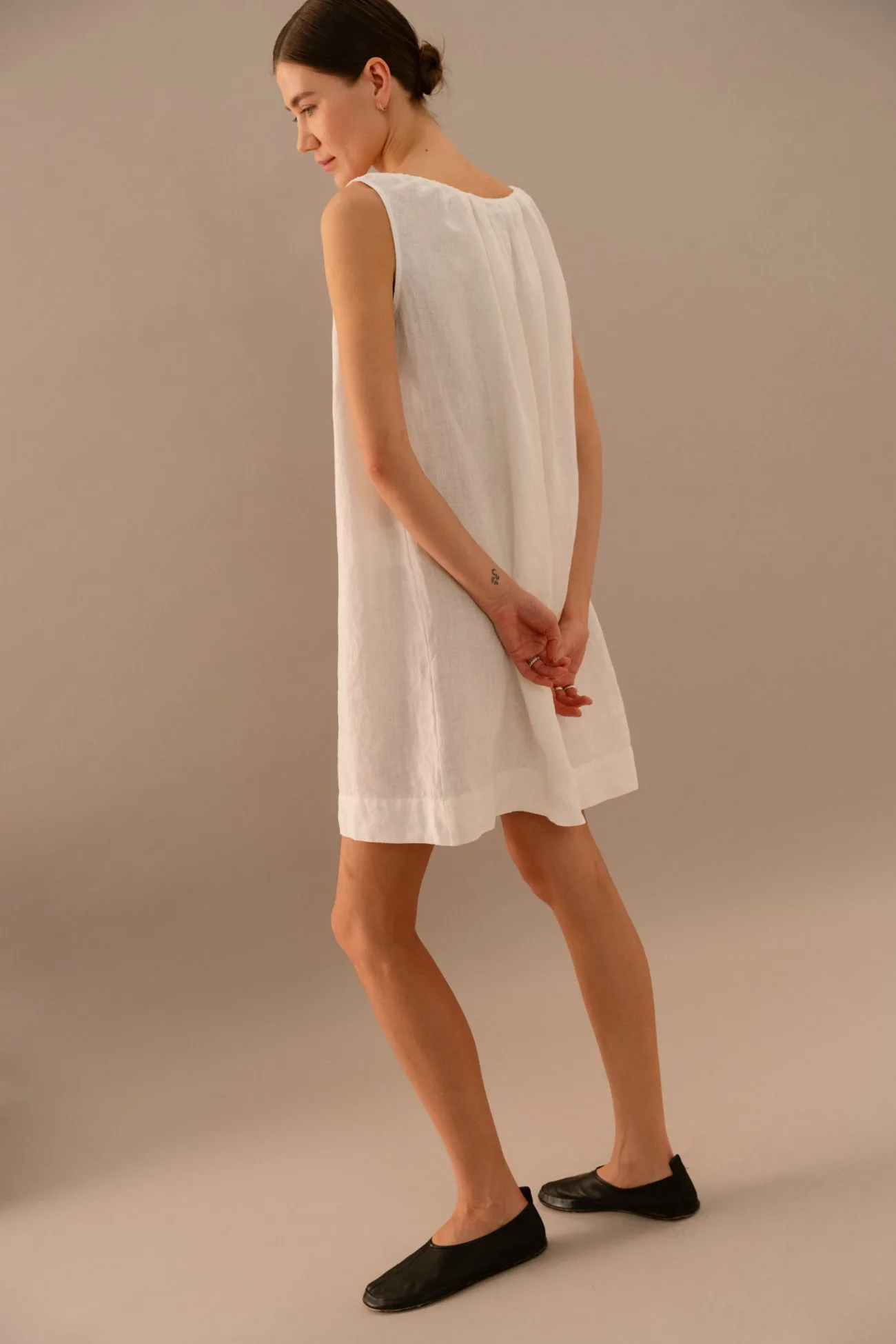 Back view of white linen sleeveless mini dress with relaxed straight silhouette