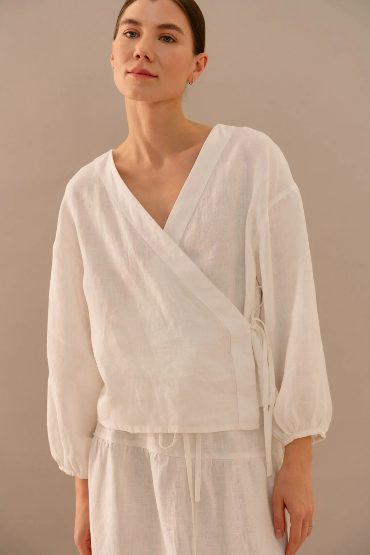 Milky white linen wrap top with V-neckline and side tie detail, worn with matching tiered linen skirt