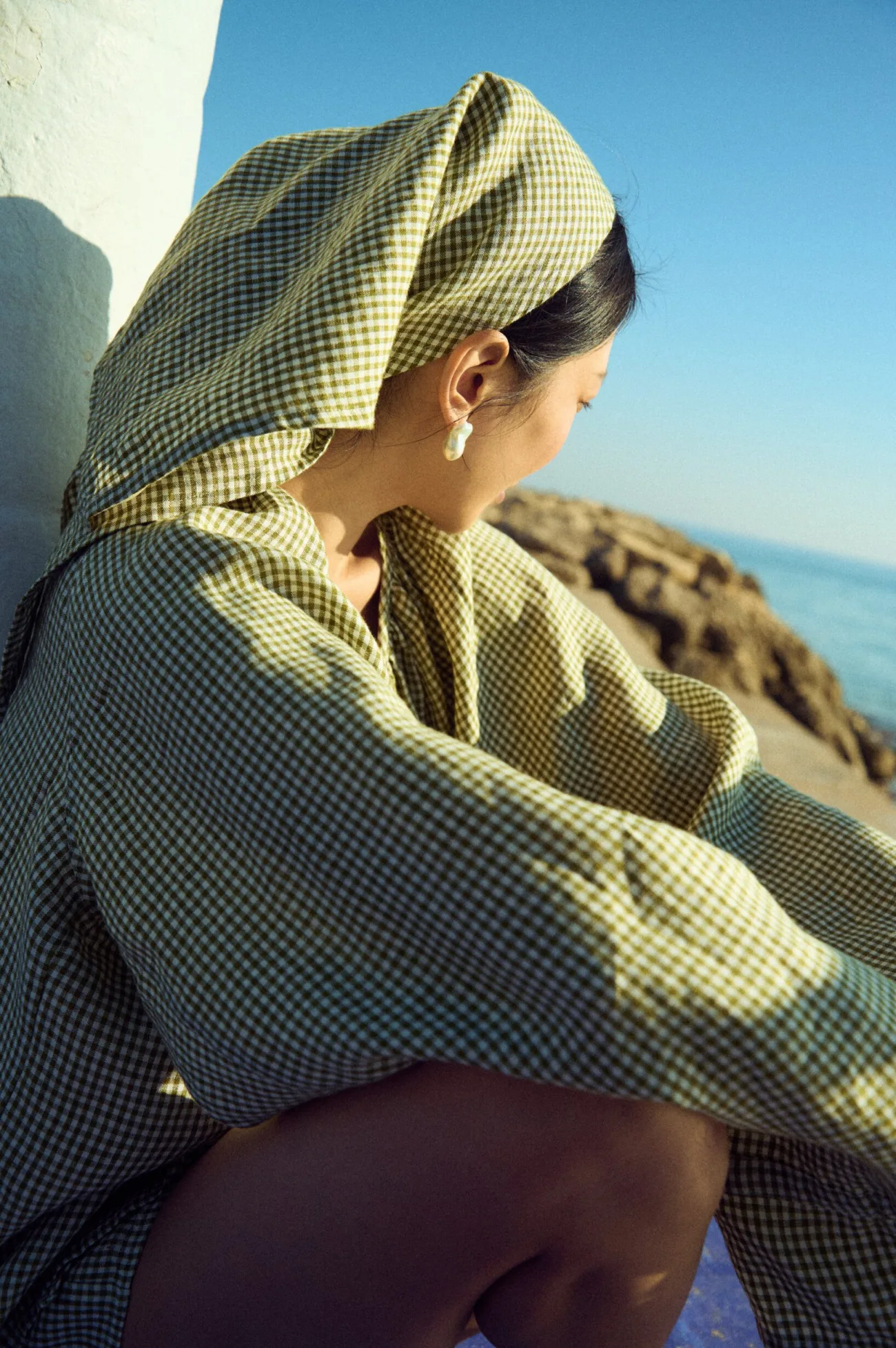 Moss green mini gingham triangle headscarf draped softly and tied at the back, paired with a relaxed gingham blouse