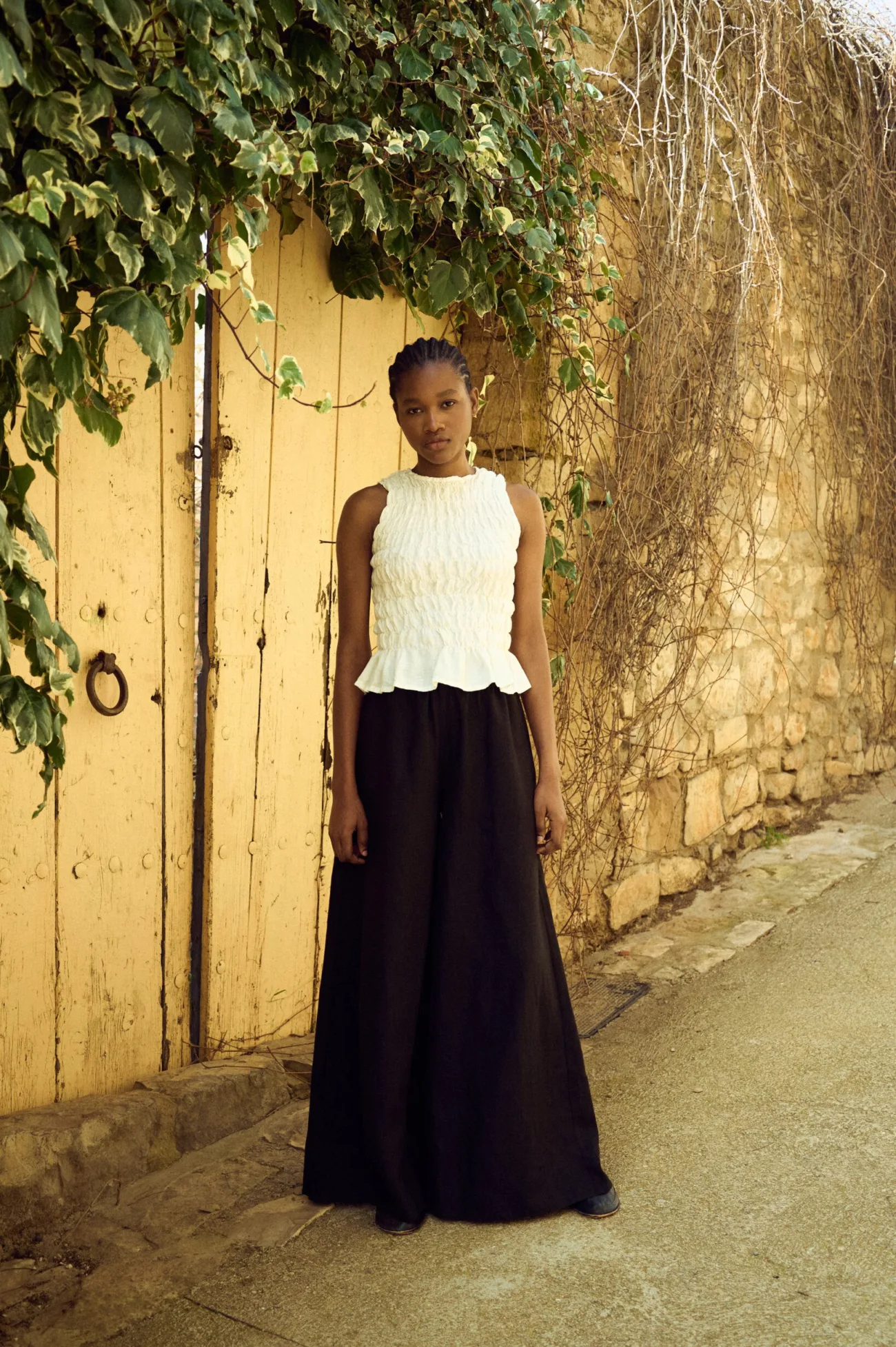 Milky white linen top featuring elasticated smocking through the body and a subtle flared hem, styled with black linen culottes