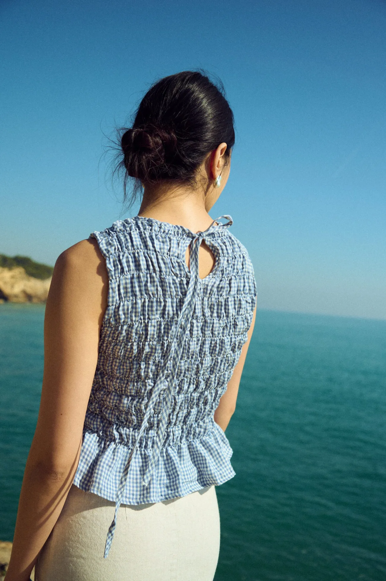 Sleeveless dusty blue gingham linen smocked top with textured finish and back tie fastening