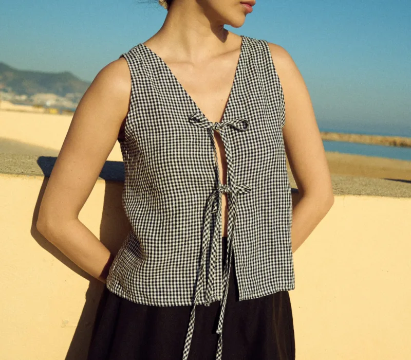 Black gingham linen blouse with adjustable tie closure worn with a black linen mini skirt