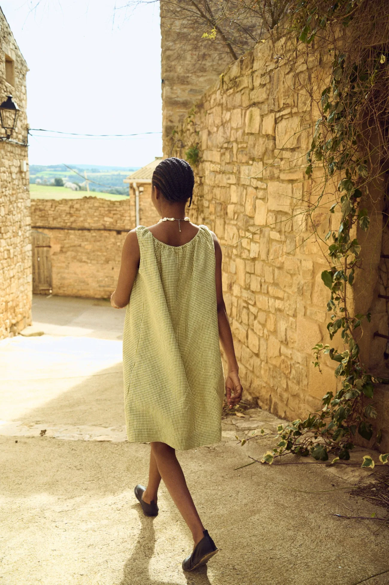 Sleeveless green mini gingham linen dress with airy silhouette viewed from the back