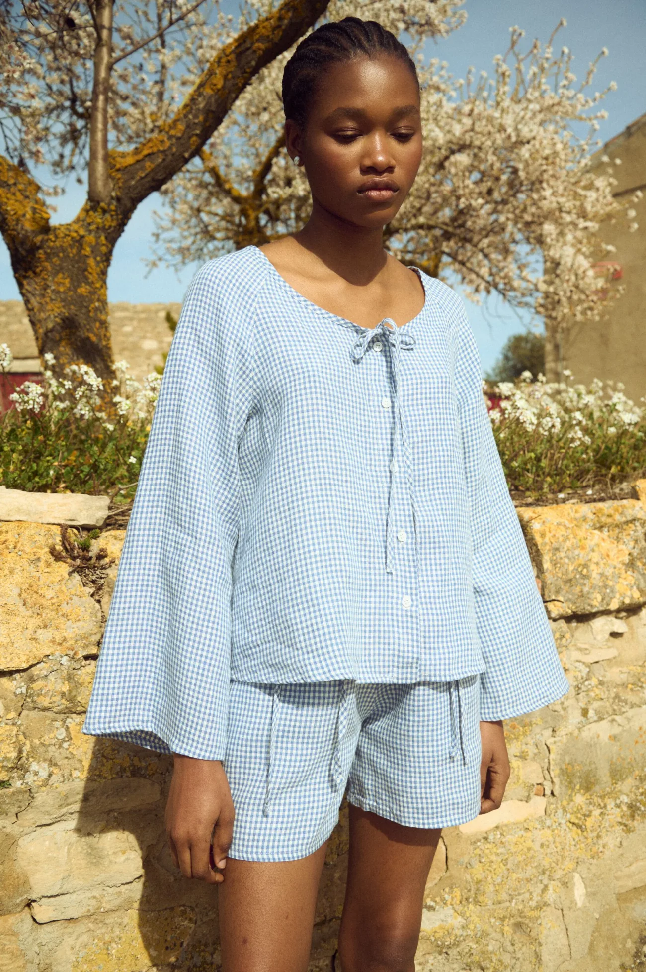Blue gingham linen top with button front, tie neckline and wide sleeves, paired with matching shorts