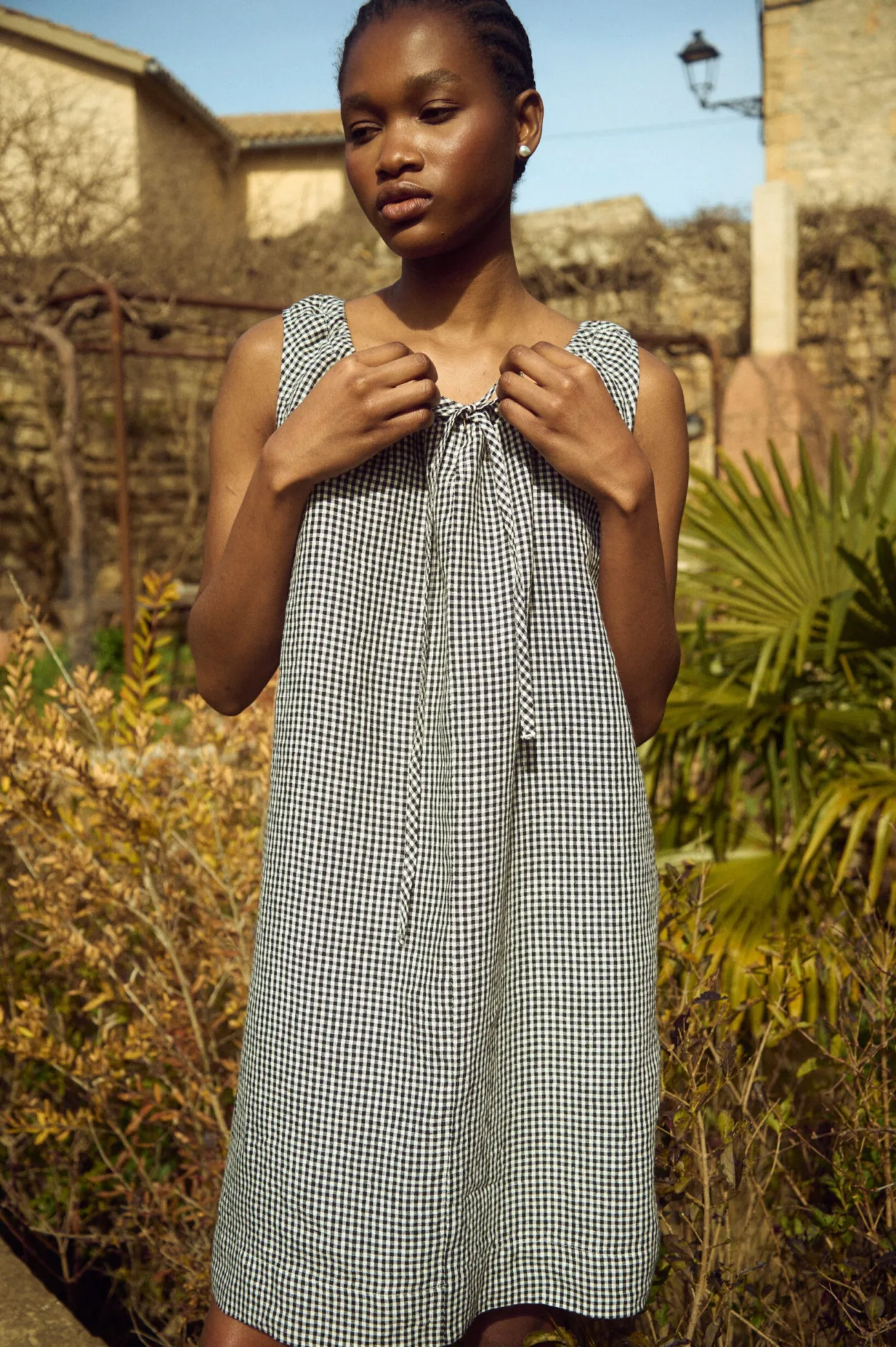 Relaxed black gingham linen mini dress with adjustable tie-front neckline and soft, draped volume