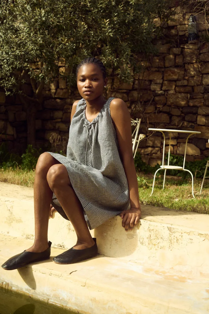 Sleeveless black gingham linen dress featuring a softly gathered neckline with delicate tie detail