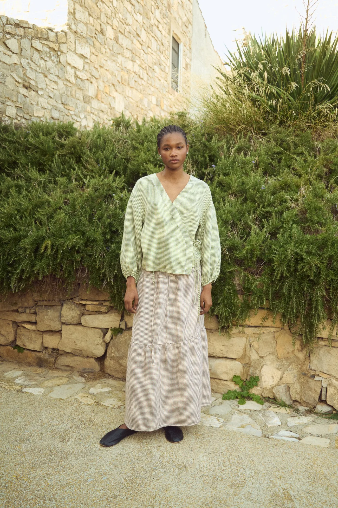 Brown gingham linen maxi skirt with gathered tier and relaxed, flowing silhouette, paired with a green gingham linen wrap top