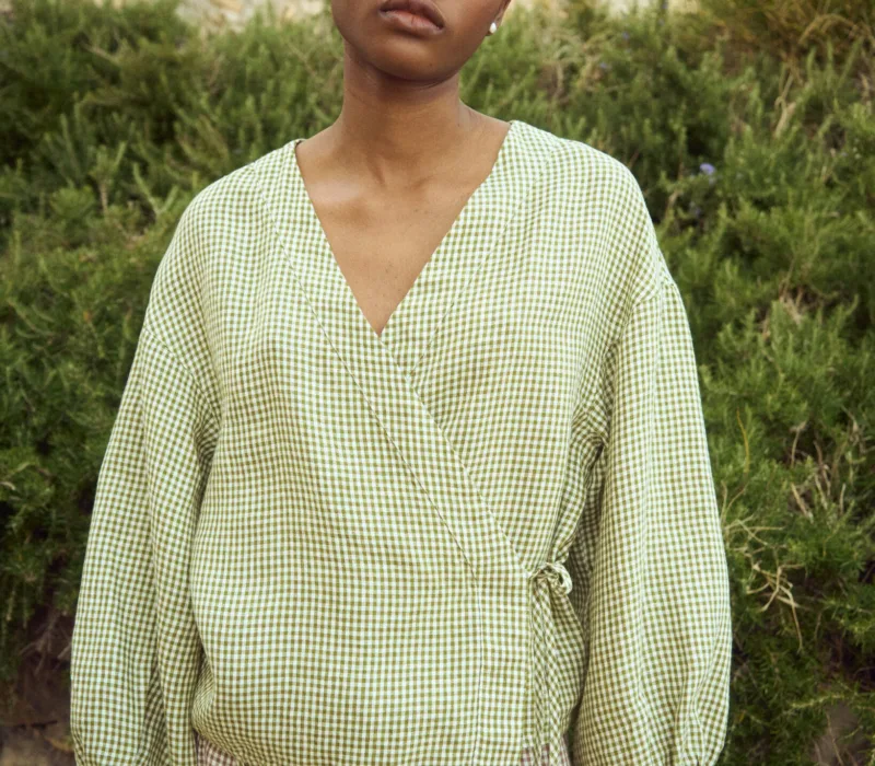Green mini gingham linen wrap top with soft V neckline and adjustable side tie, paired with a brown gingham linen skirt