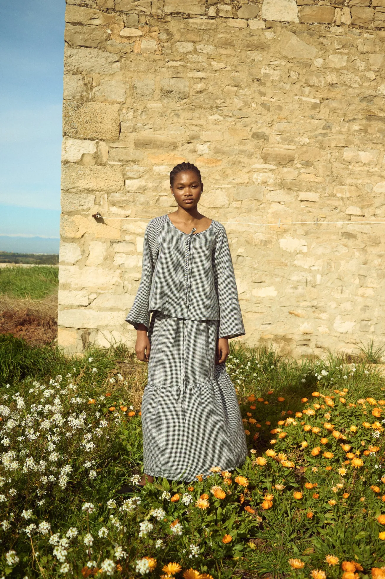 Black gingham linen skirt with gathered tier and relaxed, flowing shape, paired with a matching long-sleeve linen top