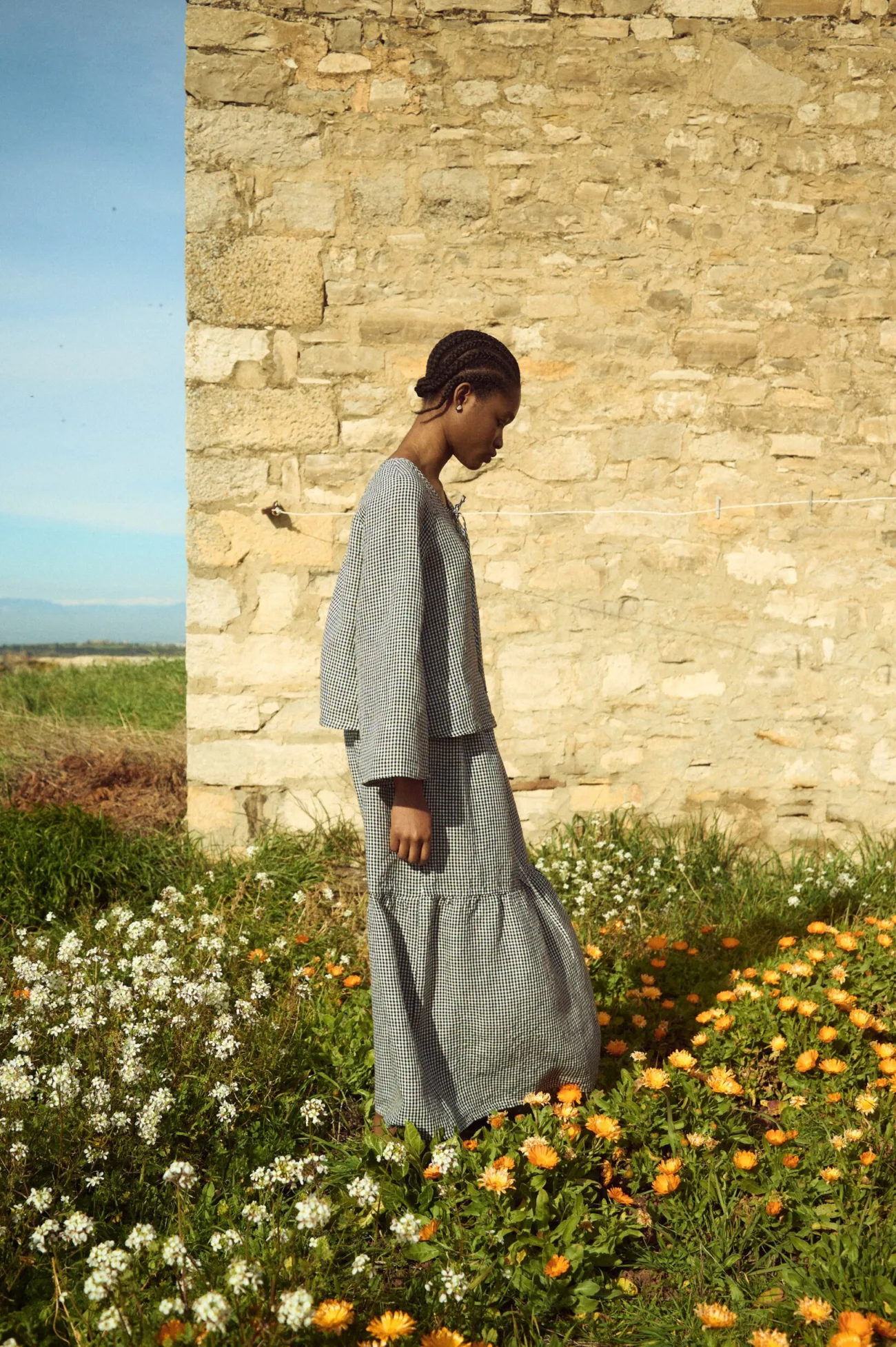 Tiered black gingham linen skirt with soft volume and airy movement, paired with a relaxed long-sleeve linen top