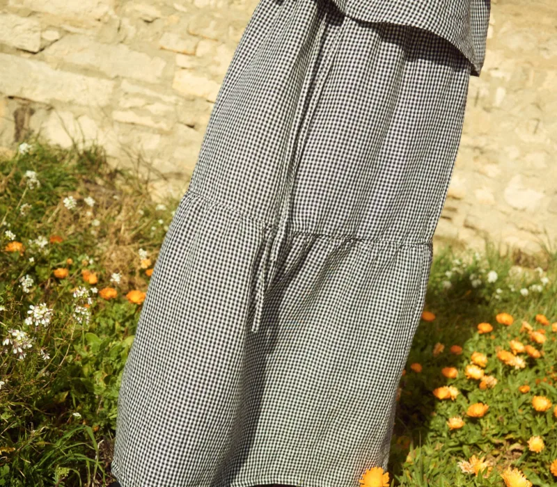 Black gingham linen skirt featuring a gathered lower tier and relaxed, flowing silhouette