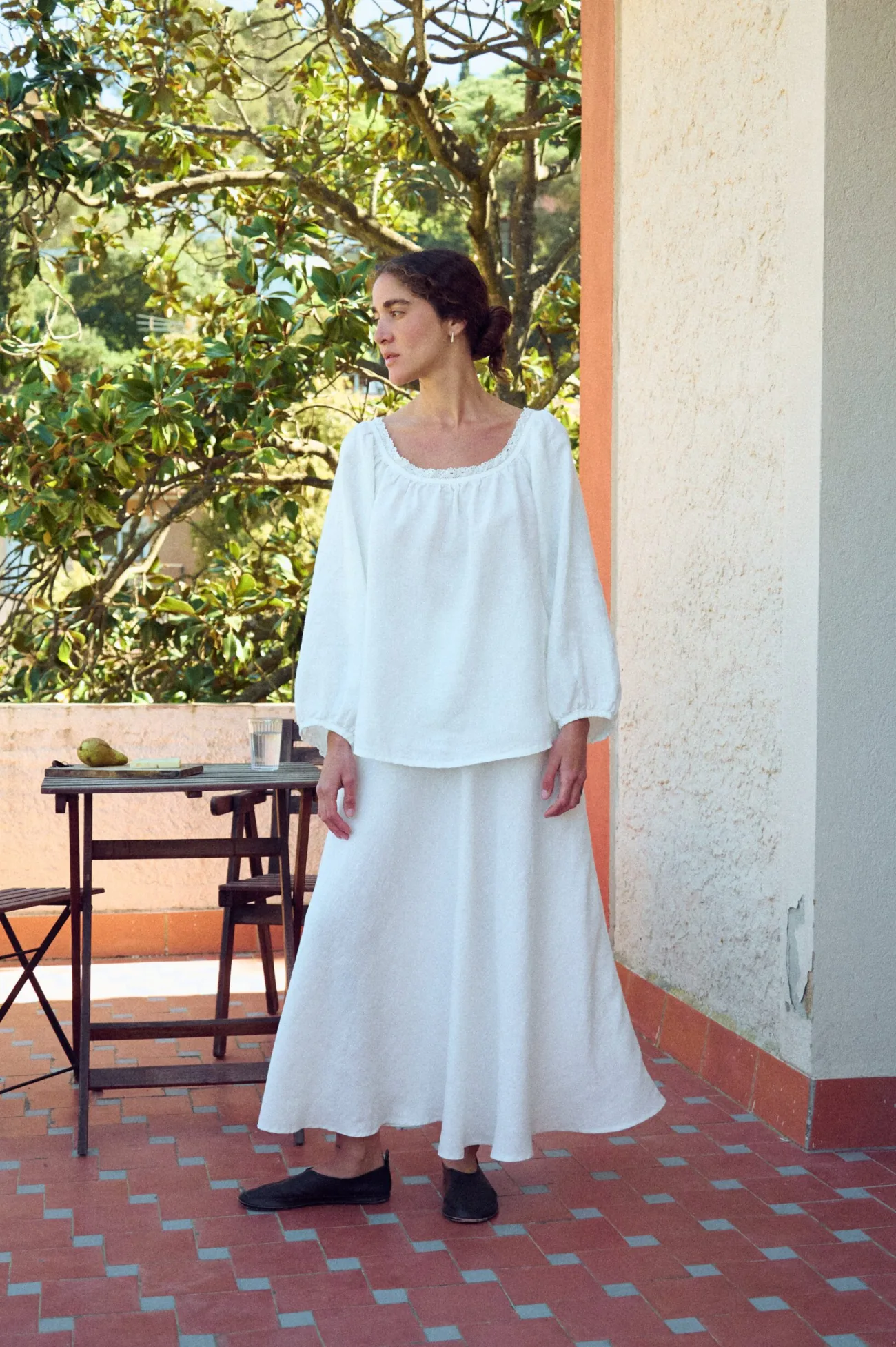 Milky white linen blouse with lace-trim scoop neckline and long sleeves, paired with a matching flowing skirt