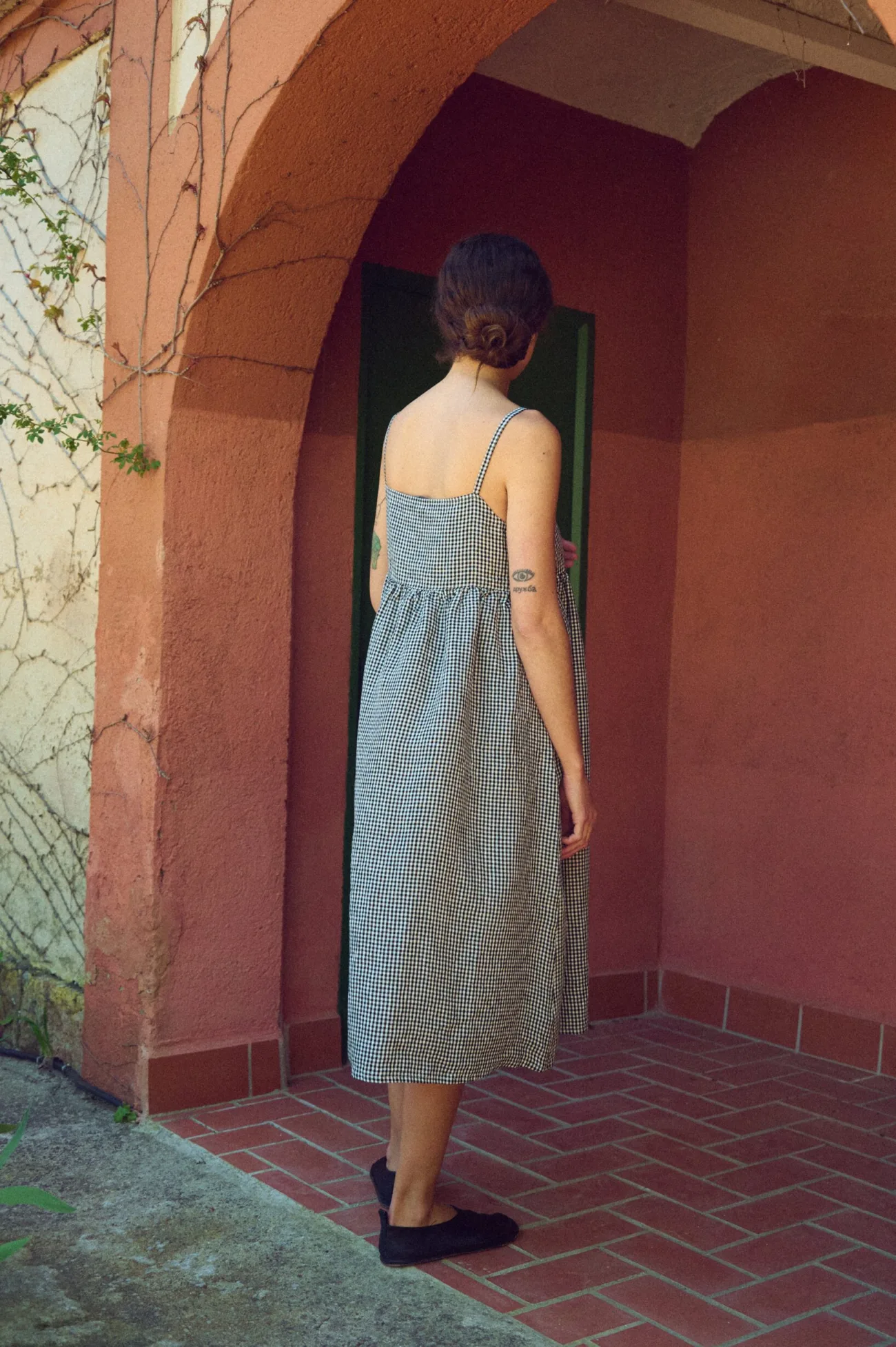 the back view of midi length summer linen dress with straps in black and white gingham
