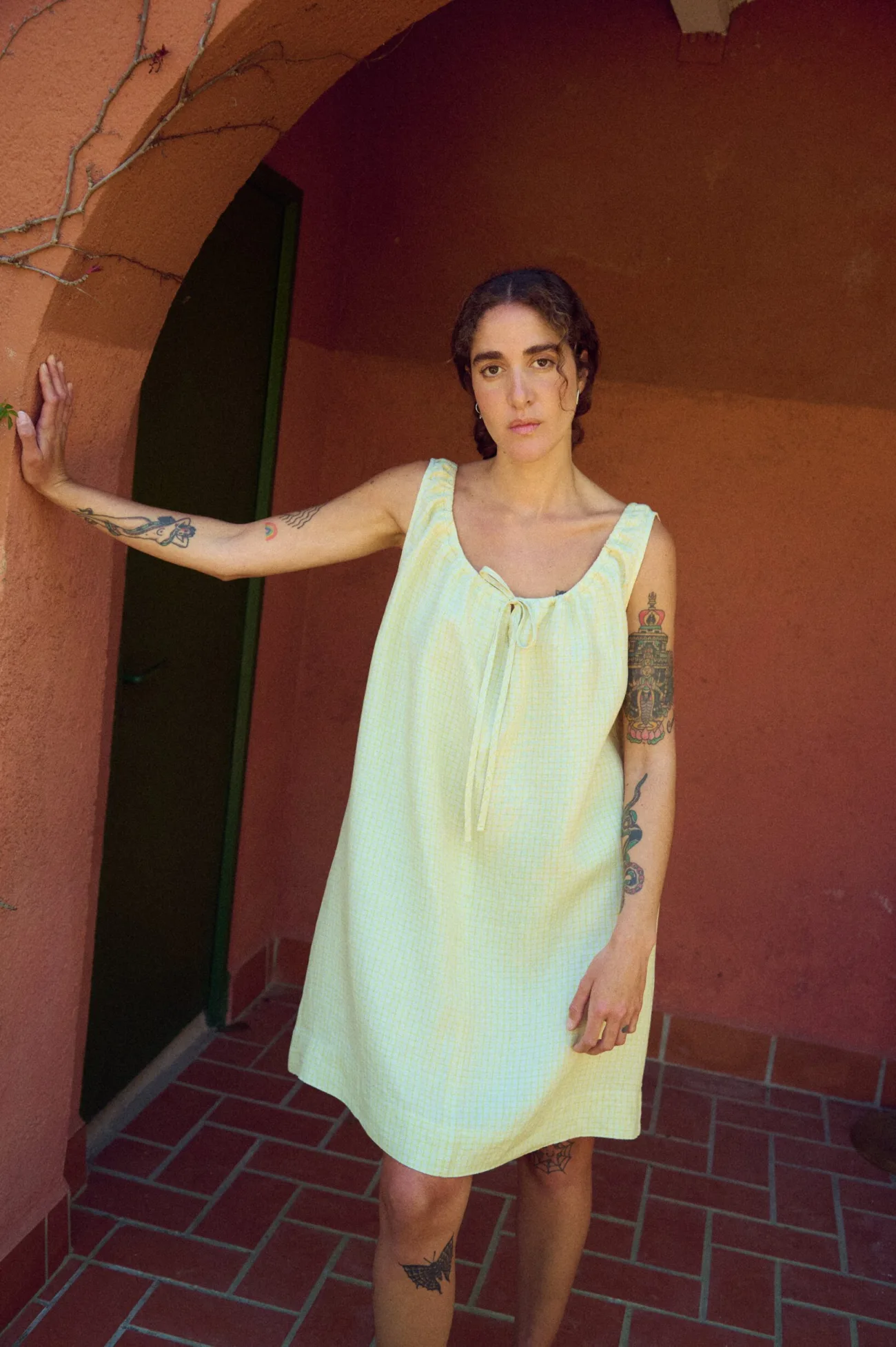 model wearing sleeveless mini linen dress in apple checked linen with adjustable neckline