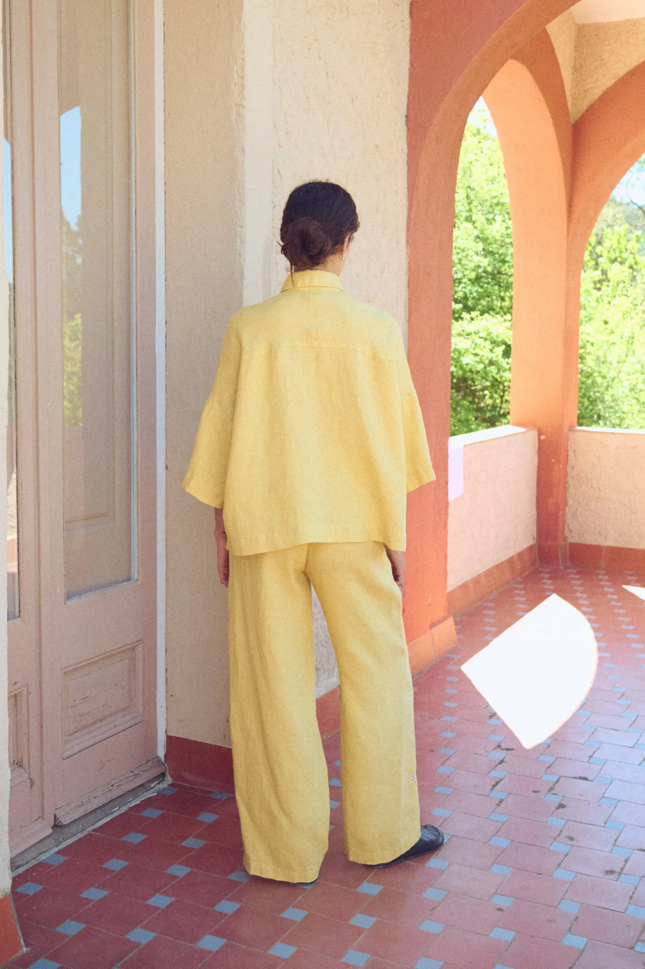 Relaxed wide-leg yellow linen pants with a fluid, easy drape, featuring a high-rise elastic waistband and a clean, minimal finish at the back for an effortless, laid-back silhouette