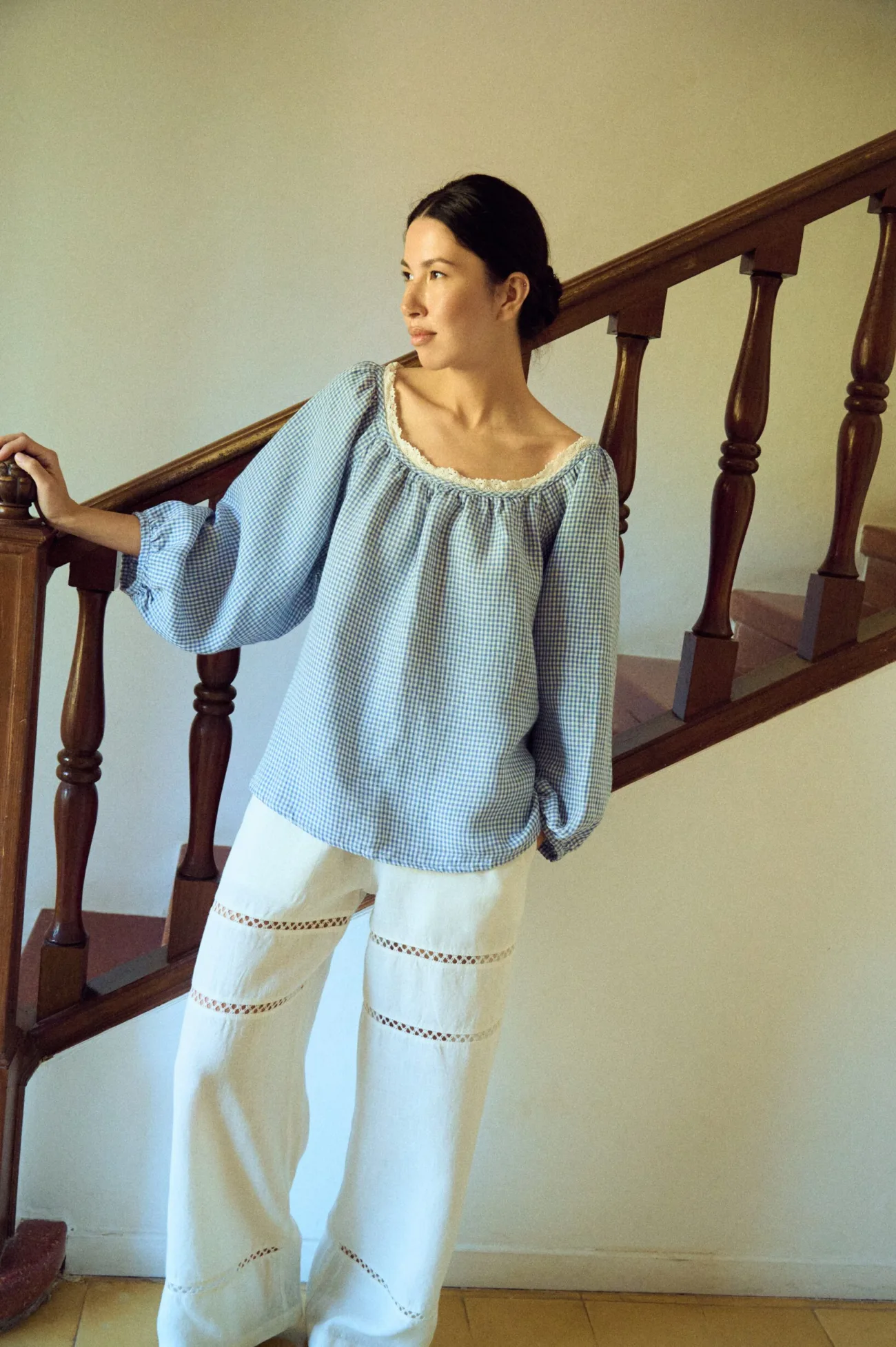 model wearing white lace linen pants styled with blue gingham blouse with lace details