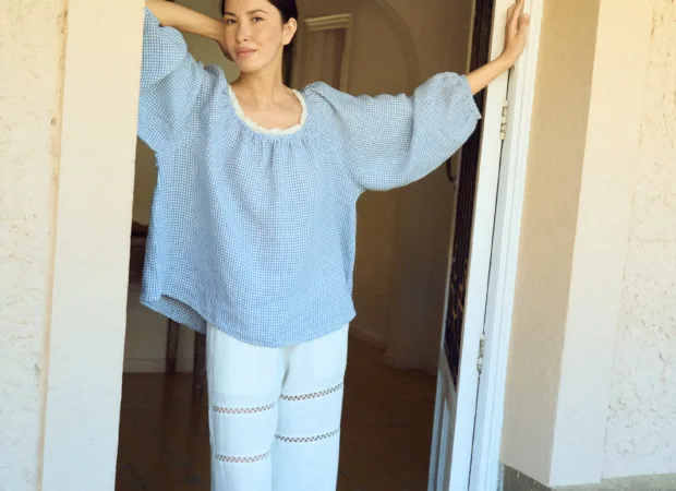 model wearing blue gingham blouse with lace neckline styled witj white lace linen pants