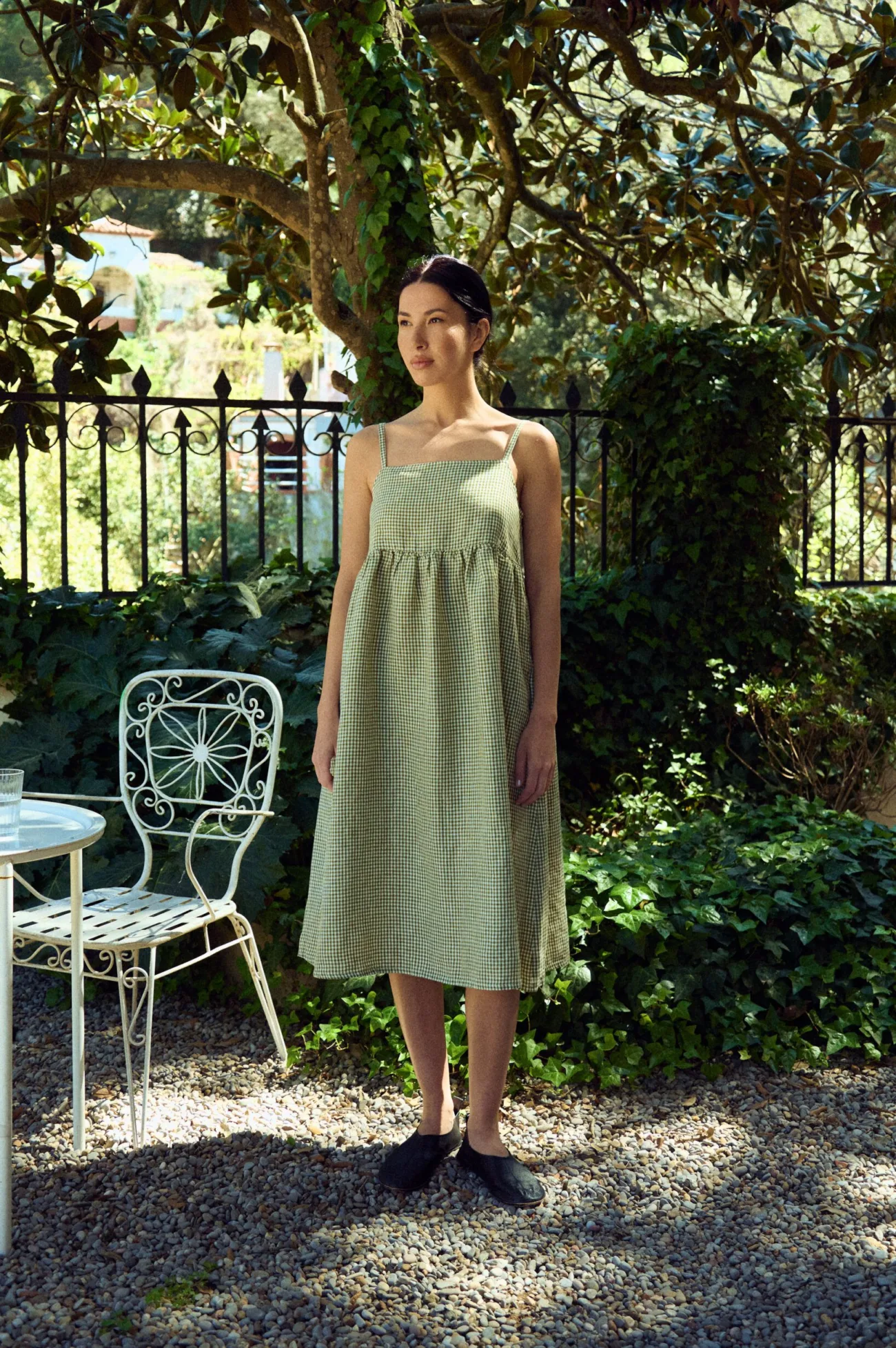 woman wearing green gingham midi linen dress in summer garden