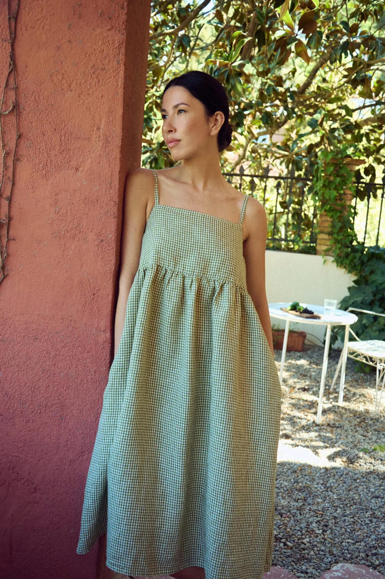 model wearing midi length green gingham linen dress with spaghetti straps and pockets