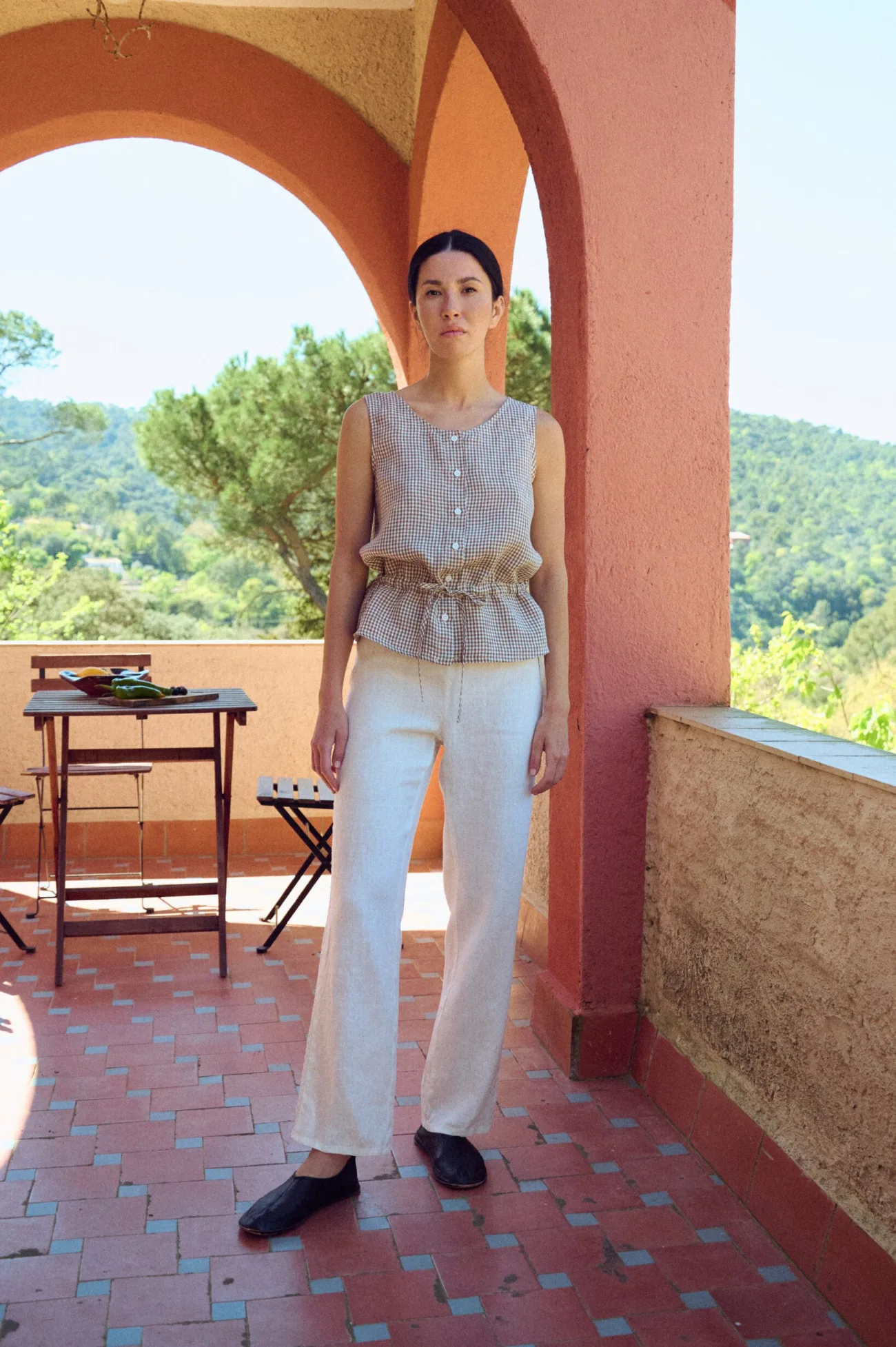 model wearing gingham sleeveless linen top in brown and white paired with straight white linen pants